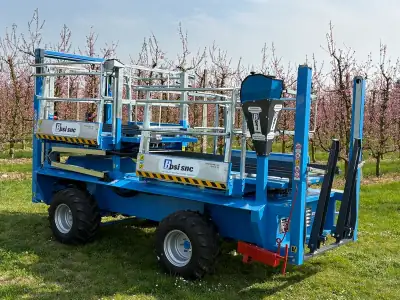 Bosi — carro raccolta frutta semovente al lavoro nel frutteto romagnolo tra peschi in fiore a Faenza